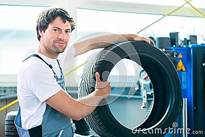Auto mechanic changing tire in workshop Stock Photo