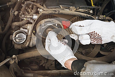 An auto mechanic checks the condition of an old timing belt for various defects Stock Photo