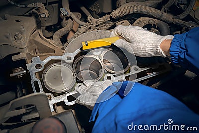 An auto mechanic with a flashlight inspects the engine block and pistons. Repair services Stock Photo