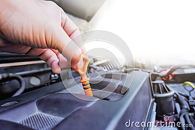 Auto mechanic hand is pulling the oil dipstick for checking lube level Stock Photo