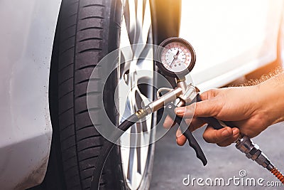 A auto mechanic inflates a tire with an air tire inflating gun Stock Photo