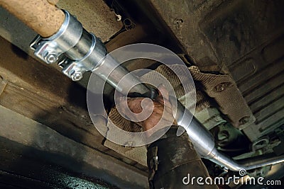 Auto mechanic installs a new car exhaust pipe Stock Photo