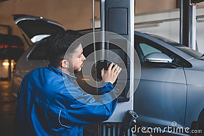 Auto mechanic lifts a car on a lift. Car repair Stock Photo