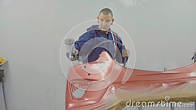 Auto painter spraying red paint on car front bumper in special booth Stock Photo