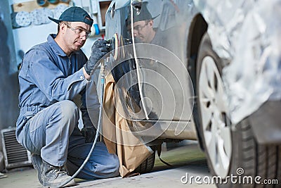 Auto repairman grinding autobody bonnet Stock Photo