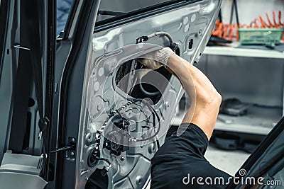 Auto service worker disassembles car door for repair, restoration, tuning car sound or installing noise insulation or Stock Photo
