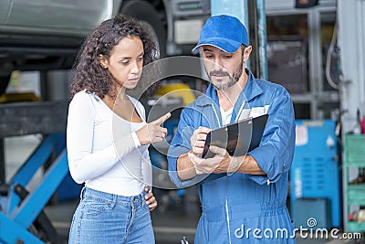 Auto services and Small business concepts. Customer and mechanic with checklist discussing work in auto service center Stock Photo