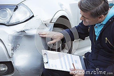 Auto Workshop Mechanic Inspecting Damage To Car And Filling In R Stock Photo