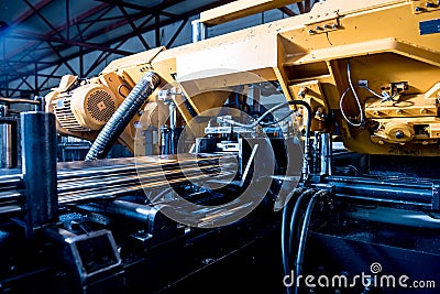 Automatic band saw machine with water coolant cutting metal pipes. Stock Photo