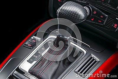 Automatic gear stick with red stich of a modern car. Car interior details. Dashboard with buttons. Stock Photo