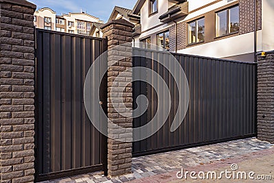 Automatic metal gates with decorative brick columns on the street side. Stock Photo