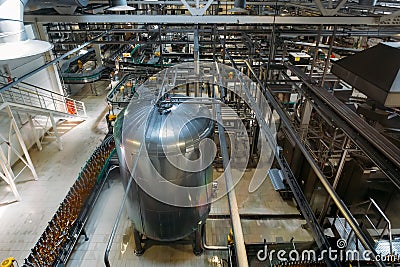 Automatic modern production line at brewery. Conveyor line and vats for fermentation and pasteurization Editorial Stock Photo