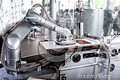 Automatic robotic hand moving tiny bits of chocolate Stock Photo