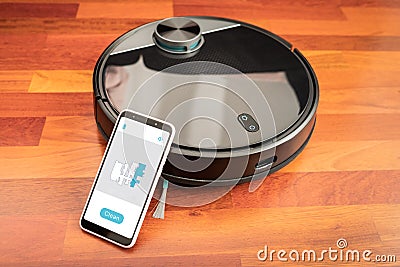 Automatic vacuum cleaner robot to clean the floor and help in housework controlled by an smart phone with an app Stock Photo