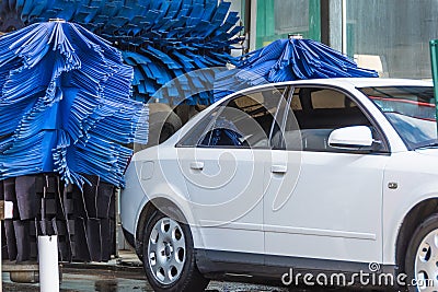 Automatic wash blue brush in action, white car comes out ready clean Stock Photo