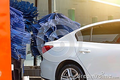 Automatic wash blue brush in action, white car comes out ready clean Stock Photo