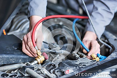 Automobile air-conditioner servicing. mechanic connecting pipes for freon refill Stock Photo
