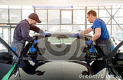 Automobile special workers replacing windscreen of a car in auto service Stock Photo