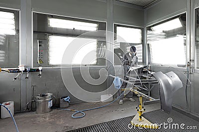 Automotive industry - engineer painting and working on a gray body of a car and wearing protective gear Editorial Stock Photo