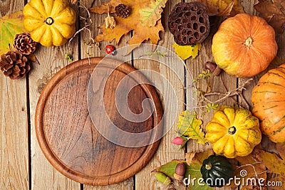 Autumn background with cutting board, fall leaves and pumpkin over wooden table. Stock Photo