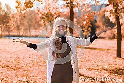 Autumn beautiful portrait of a young girl in the park with foliage. teenager smiles and hands up Stock Photo