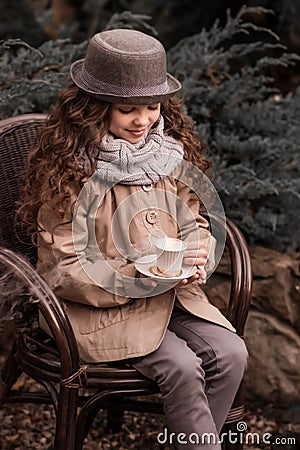 Autumn child girl drinking hot beverage in the garden cafe Stock Photo