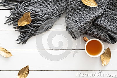 Autumn composition. Feminine desk table with knitted scarf, tea cup, fall leaves on wooden white background. Flat lay, top view. Stock Photo