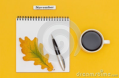 Autumn composition. Text November Coffee Cup, open notepad with pen and yellow oak leaf on yellow paper background. Top view Flat Stock Photo
