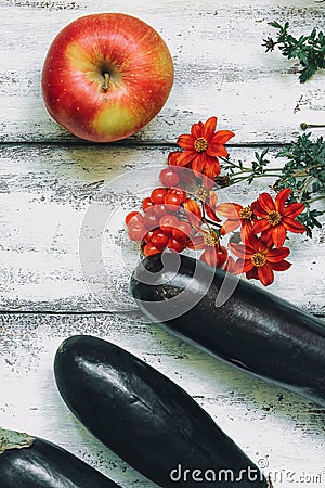 Autumn composition on a wooden background. Apples, viburnum, eggplant and flowers Stock Photo