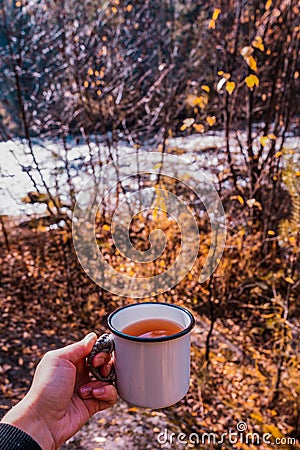 Autumn drink. Enameled cup of coffee or tea on autumn landscape outdoors. tea in an iron travel mug in the autumn forest. Stock Photo