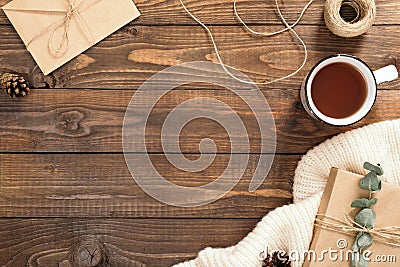 Autumn flatlay composition. Frame made of craft paper envelope, cup of tea, rope, gift box, white knitted scarf on wooden Stock Photo