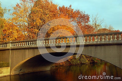 Autumn foliage surrounds a stone bridge spanning a lake Stock Photo