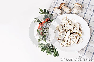Autumn food arrangement. Composition of whole and sliced porcino mushrooms, ceps on plate. Rowan berries, leaves, fir Stock Photo