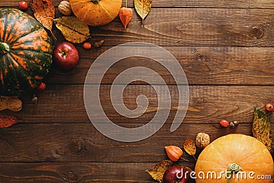 Autumn frame made of pumpkins, dried fall leaves, apples, red berries, walnuts, blanket on wooden table. Thanksgiving, Halloween, Stock Photo