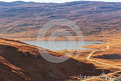 Autumn greenlandic orange tundra landscape with road to the lake and mountains in the background, Kangerlussuaq, Greenland Stock Photo