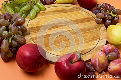 Autumn Harvest Card or Background Various Fruits Grapes Apples Plum and Pears Laying Round Wooden Tray Orange Background Above Stock Photo