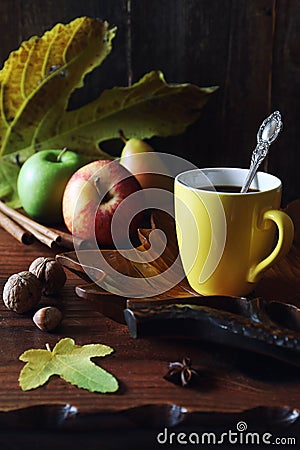 Autumn image: Yellow cup of coffee, nuts, autumn leaves and apples Stock Photo