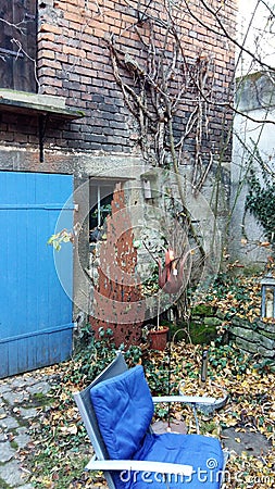 Backyard of brick house with blue door and blue garden chair Stock Photo