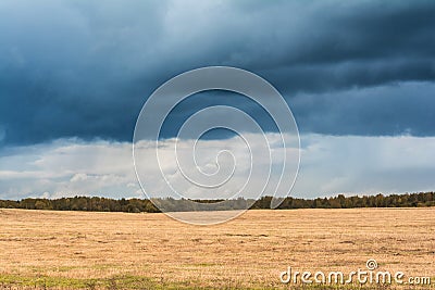 Autumn landscape with cloudy weather, large rainy clouds over a chamfered yellow field Stock Photo