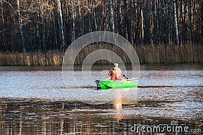 Autumn landscape with a lake, fisherman`s silhouette in a boat, tree reflections in the water, autumn time Stock Photo