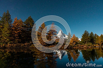 Autumn larches against the background of the Matterhorn and autumn in the Alps. The clear water of the mountain lake Stock Photo