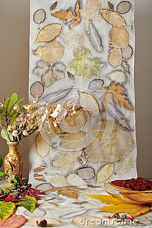 Autumn leaves, nuts, berries and a vase with a dried bouquet on a background of hand-dyed stripe of fabric using an eco-print Stock Photo