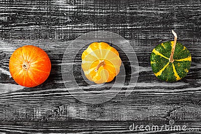 Autumn minimalistic composition with orange, yellow and green pumpkins on dark wooden background. top view Stock Photo