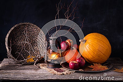 Autumn mood concept. Harvest stillife pimpkin, apples, gas lantern, yellow maple leaf. Stock Photo
