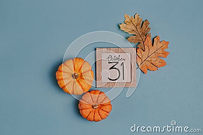 Autumn October flat lay. Orange mini pumpkins and calendar date in wooden frame. Halloween day. Blue background. Oak leaves. Fall Stock Photo