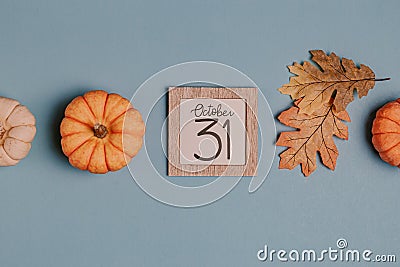 Autumn October flat lay. Orange mini pumpkins and calendar date in wooden frame. Halloween day. Blue background. Oak leaves. Fall Stock Photo