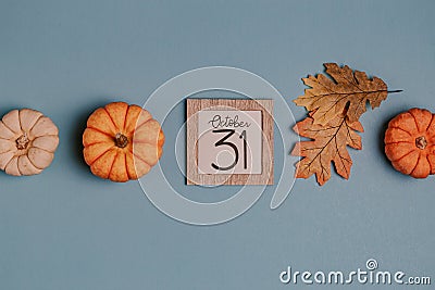 Autumn October flat lay. Orange mini pumpkins and calendar date in wooden frame. Halloween day. Blue background. Oak leaves. Fall Stock Photo