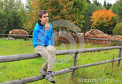 Teenage boy sitting on a fence Stock Photo