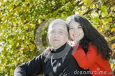 Autumn park outdoor family portrait of smiling adult daughter hugging her senior father Stock Photo