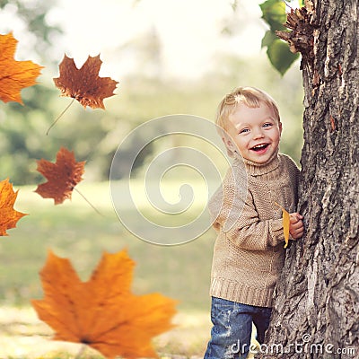 Autumn portrait of happy child playing having fun with flying yellow maple leaves Stock Photo